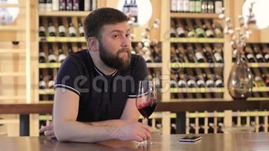 一个孤独的人拿着一杯红酒，一个年轻的人拿着一杯红酒，一个男人在一家餐馆喝红酒